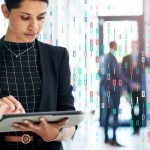 Professional using a tablet with digital data overlays, representing enterprise analytics, AI, and data-driven decision-making.