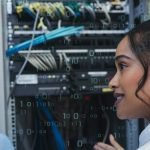 Two technology professionals discussing network equipment in a server room, with binary code overlays representing digital infrastructure and connectivity.