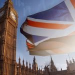 Elizabeth Tower and the Houses of Parliament in London with a Union Jack flag and digital data overlays, representing UK government, technology, and digital policy.